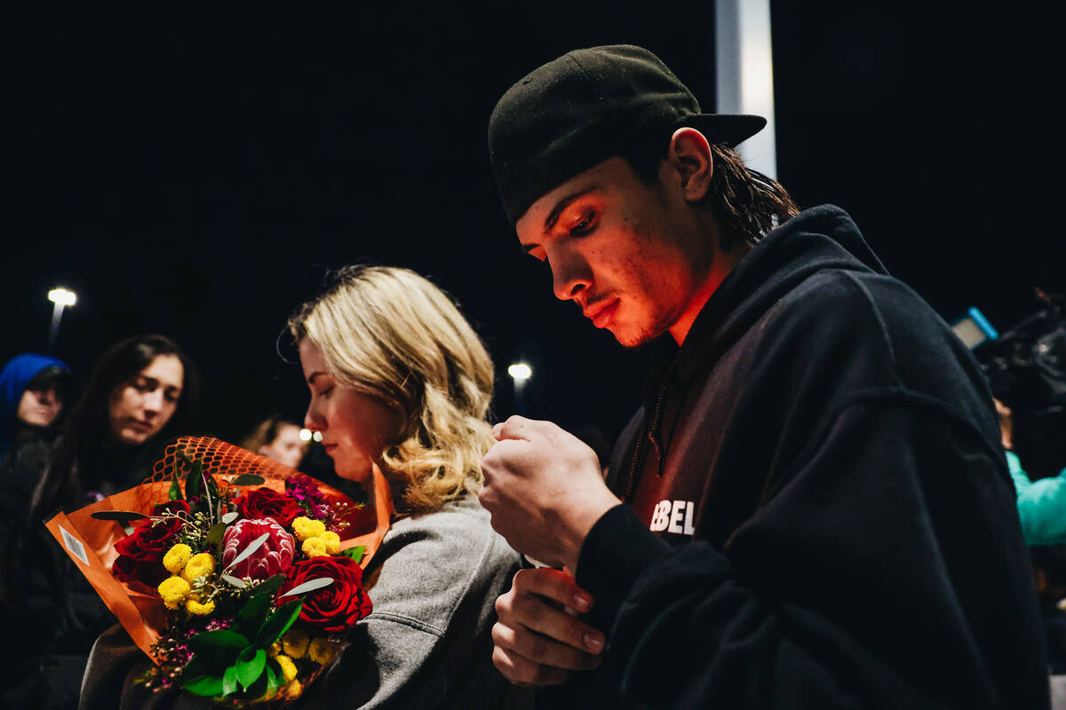 A mourner holds a candle during a vigil for Rebecca Post, Achilles Quintanilla and Leo Post-Qui ...