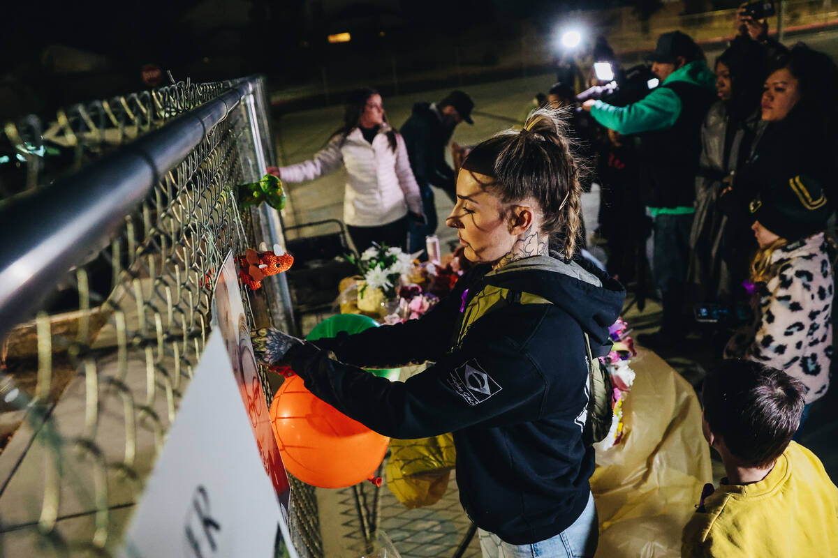A mourner attaches balloons to a fence full of posters and photographs during a vigil for Rebec ...