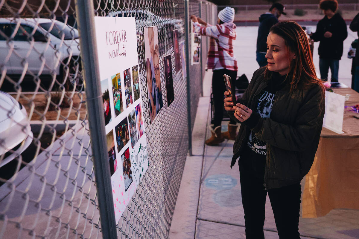 A mourner takes photos of posters and photographs strung up on a fence during a vigil for Rebec ...