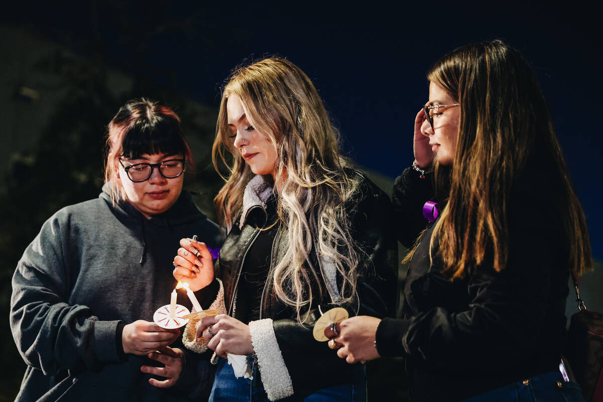 Leighonna Post, middle, lights a candle during a vigil for her mother, Rebecca Post, and brothe ...