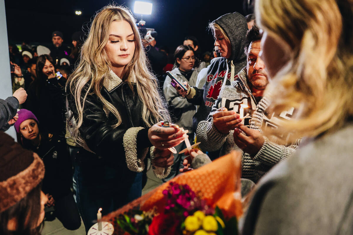 Leighonna Post lights a candle during a vigil for her mother, Rebecca Post, and brothers, Achil ...