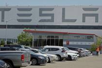 FILE - A man walks in the Tesla plant parking lot, May 11, 2020, in Fremont, Calif. Factory wor ...