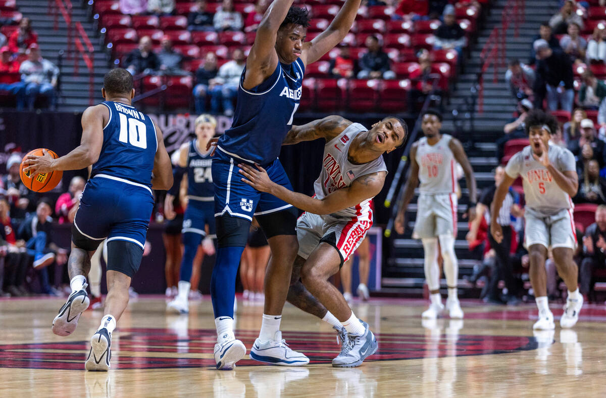 UNLV guard Luis Rodriguez (15) crashes off the chest of Utah State Aggies forward Great Osobor ...
