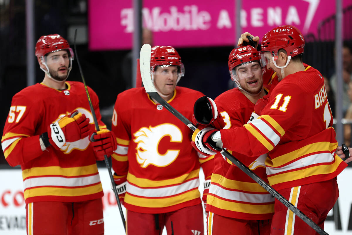 Flames left wing Andrew Mangiapane (88) congratulates center Mikael Backlund (11) on his goal d ...