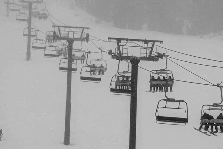 In this photo provided by Mammoth Mountain Ski Area skiers ride a lift during a snowfall at Mam ...