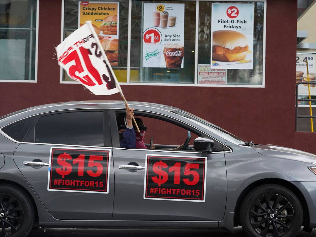 FILE - Fast-food workers drive though a McDonald's restaurant demanding a $15 hourly minimum wa ...