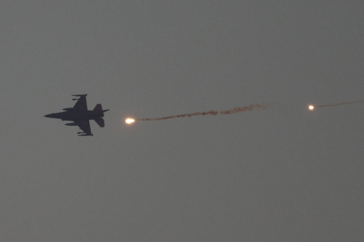 An Israeli fighter jet releases flares as it flies over the Gaza Strip, as seen from southern I ...