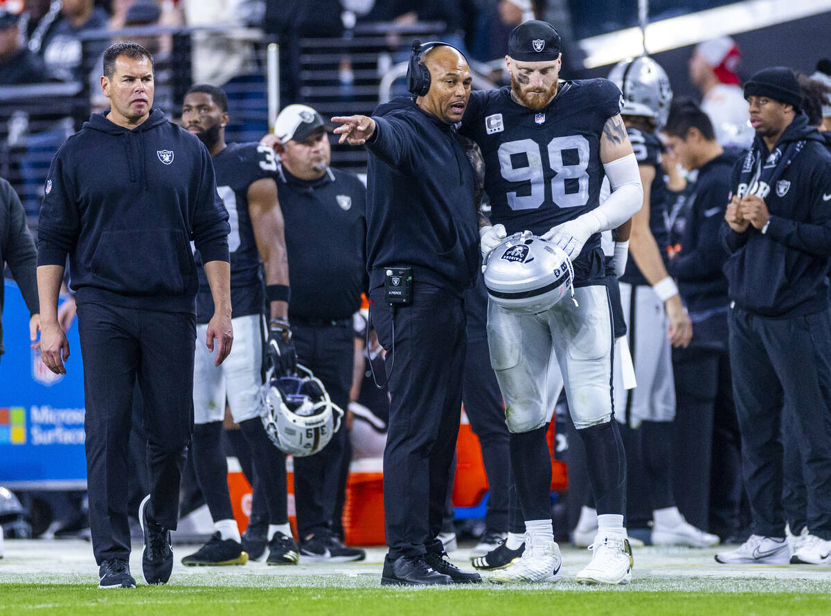 Raiders head coach Antonio Pierce talks with defensive end Maxx Crosby (98) on the sidelines ag ...