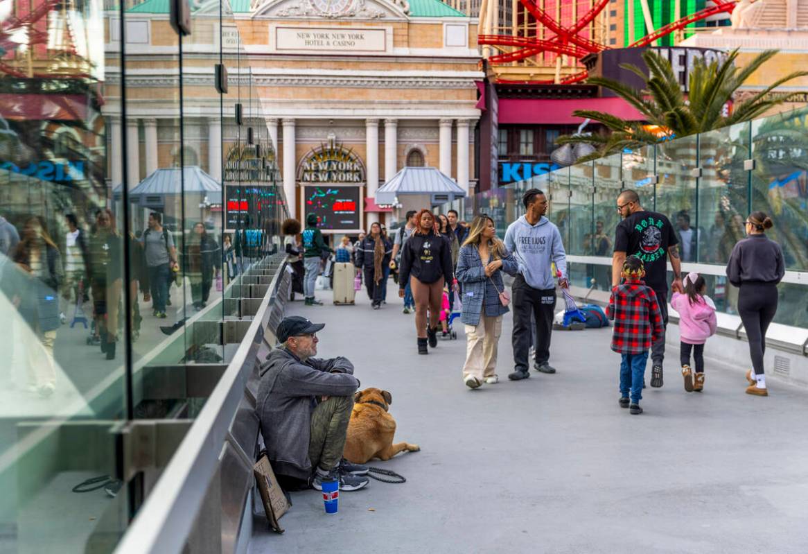 Pedestrians walk along as panhandlers and performers occupy spots along the bridge leading to N ...