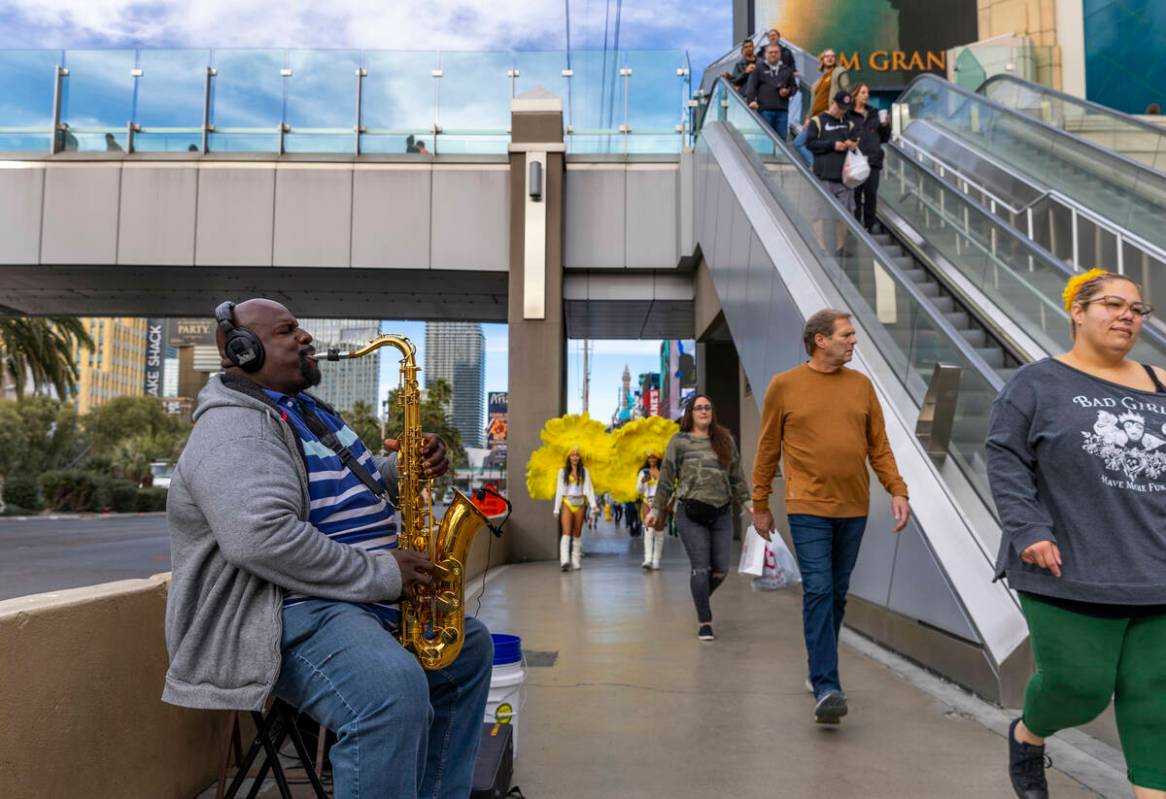 A saxophonist plays near the pedestrian bridge leading to the MGM as others walk by on Wednesda ...