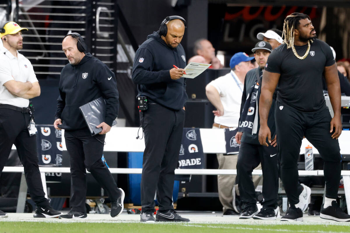 Raiders Interim Coach Antonio Pierce, center. checks his notes as his team faces the Denver Bro ...