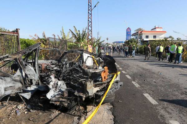 Lebanese soldiers and Civil defense workers gather next to a damaged car in the southern town o ...