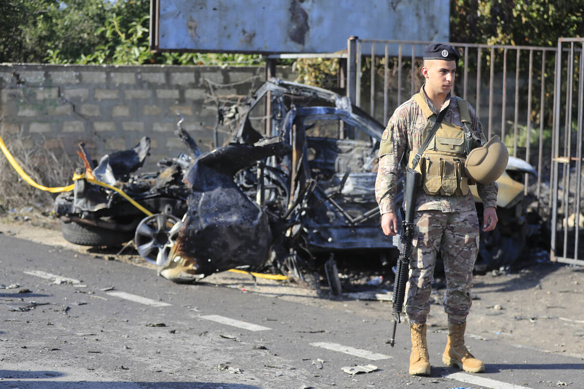 A Lebanese soldier stands next to a damaged car in the southern town of Bazouriyeh, Lebanon, Sa ...