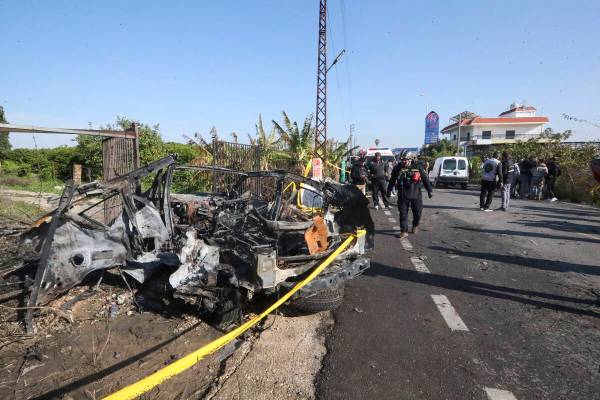 Civil defense worker searches a damaged car in the southern town of Bazouriyeh, Lebanon, Saturd ...