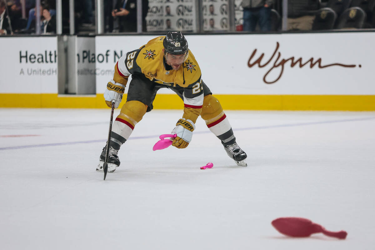 Golden Knights defenseman Alec Martinez (23) picks up plastic flamingo toys off of the ice afte ...