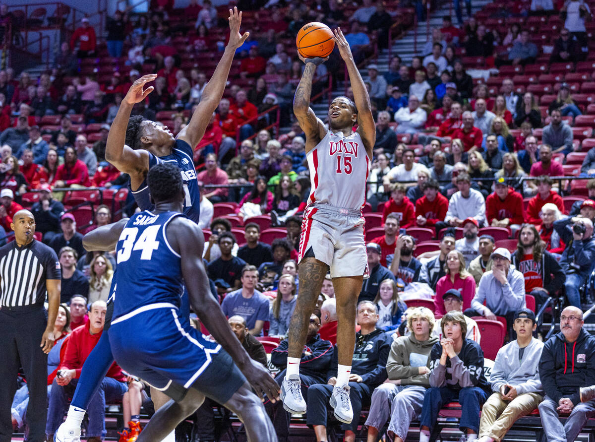 UNLV guard Luis Rodriguez (15) gets off a three-point basket attempt over Utah State Aggies for ...