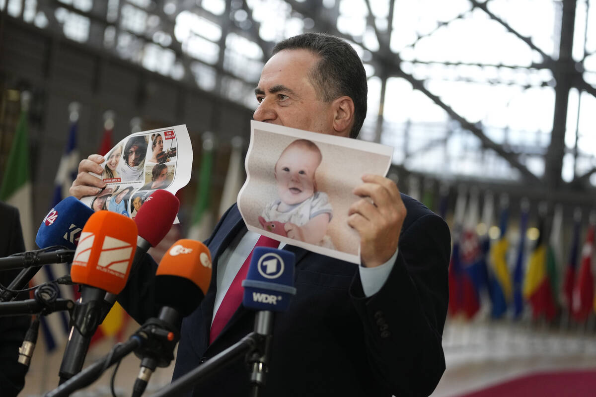 Israel's Foreign Minister Israel Katz holds up a paper photo of hostages kidnapped during the O ...