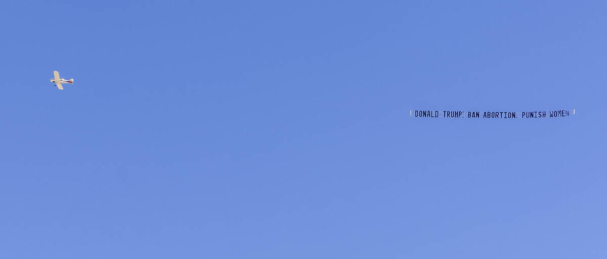 A plane with aerial advertising flys over as supporters line up outside to see Republican presi ...