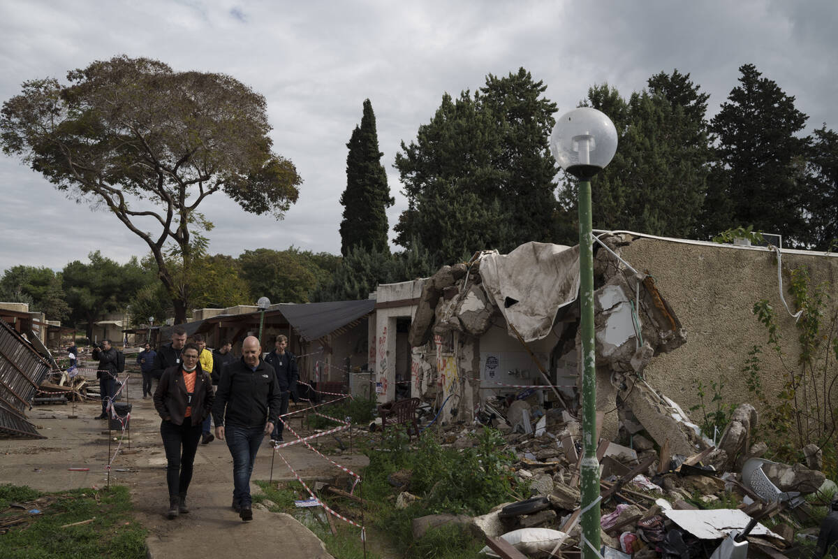 People walk past houses destroyed during the cross-border attack by Hamas on Oct. 7, as they vi ...