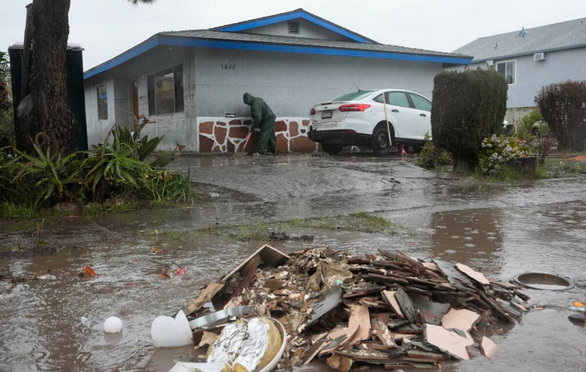 Ruben Gomez digs away some of the mud and flood debris that engulfed his parents' home in the p ...