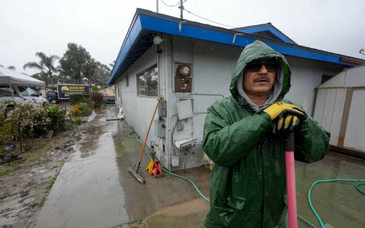 Ruben Gomez pauses as he digs away some of the mud and flood debris that engulfed his parents' ...