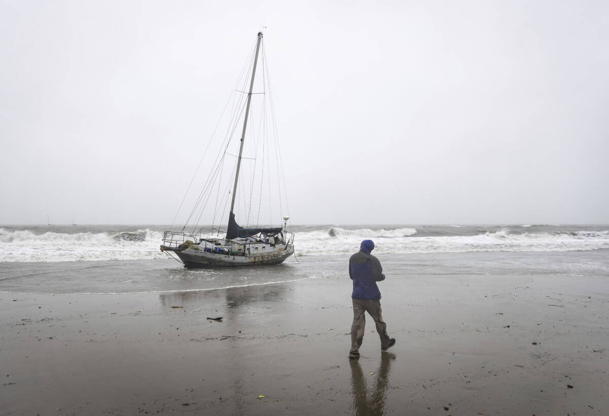 Stephen Wheeler, a Santa Barbara resident, walks past a drift boat that washed ashore during a ...