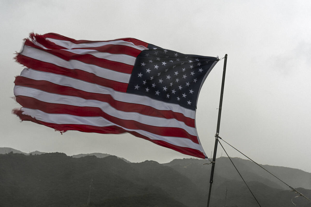 A vehicle flies the U.S. flag under heavy rain on the Interstate 210 past the Verdugo Mountains ...