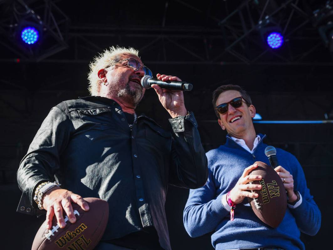 Guy Fieri, left, and Eli Manning, right, address the crowd before throwing signed footballs to ...