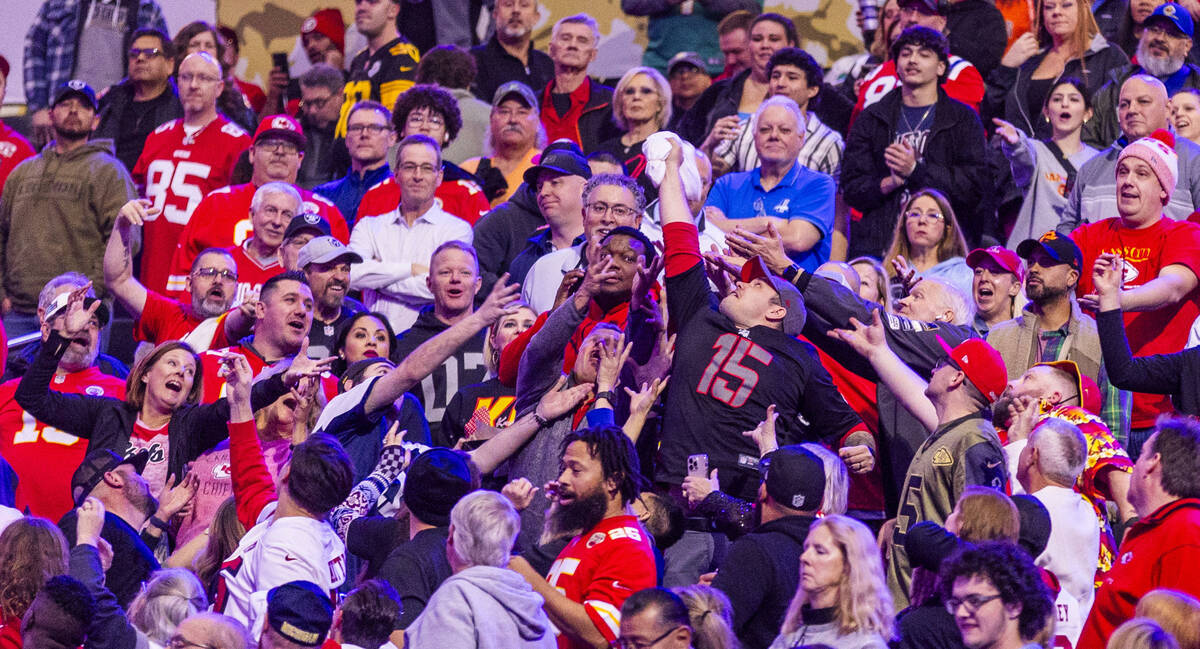 A fan makes a grab for a t-shirt tossed to the crowd during the Super Bowl Opening Night celebr ...