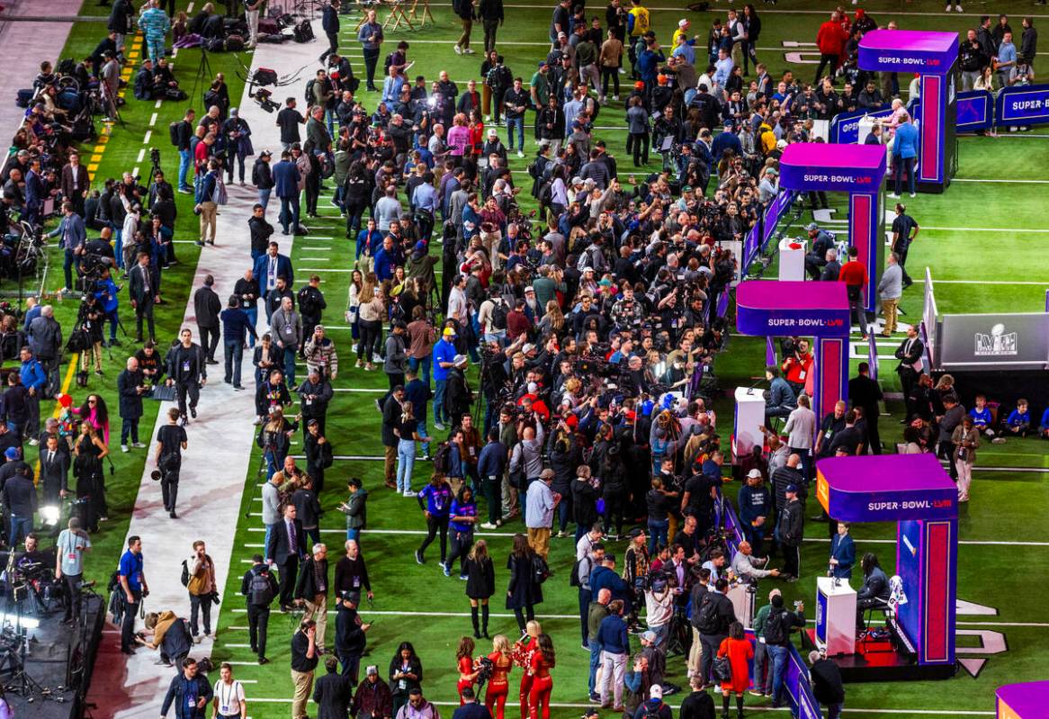 Media members and guests gather on the field as Kansas City Chiefs players and coaches take que ...