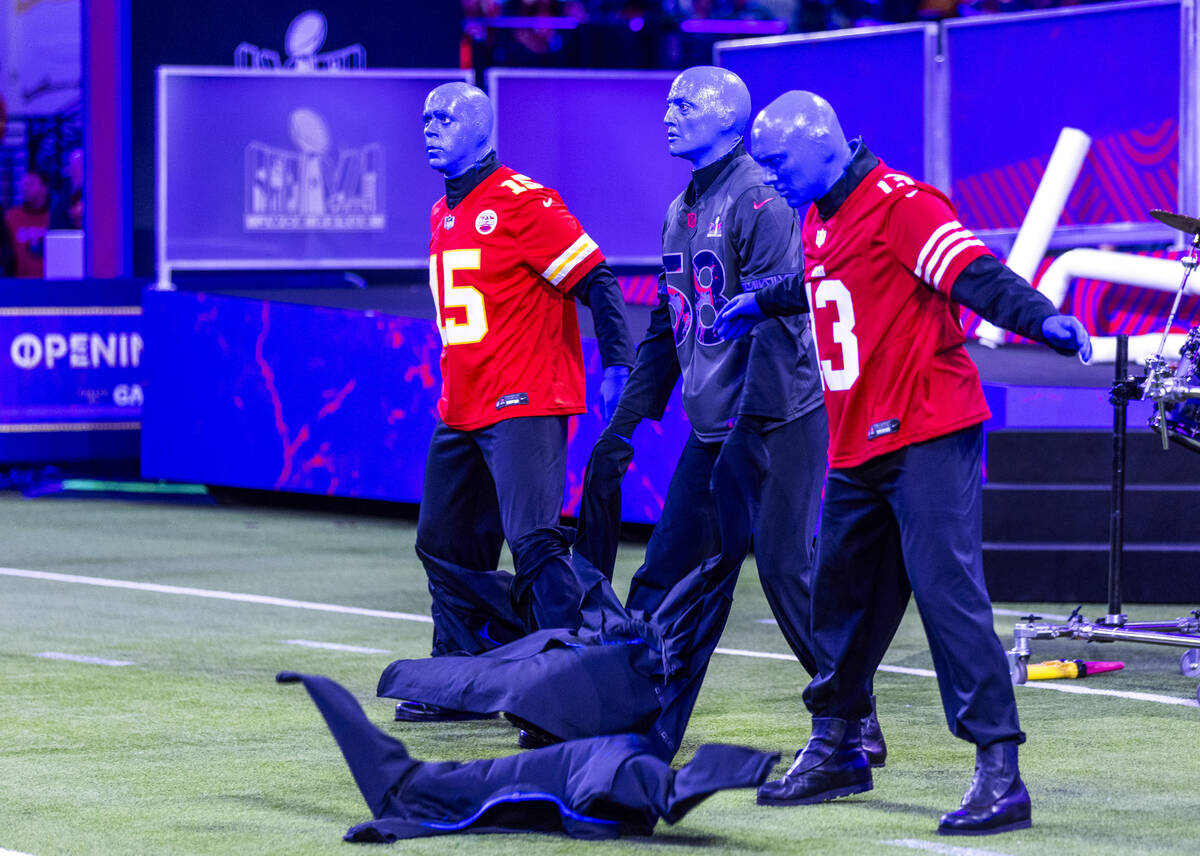 The Blue Man Group rip of their jackets to reveal jerseys during the Super Bowl Opening Night c ...