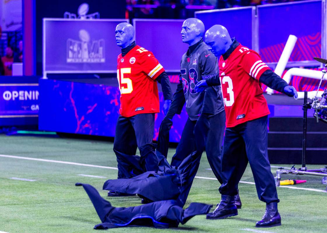 The Blue Man Group rip of their jackets to reveal jerseys during the Super Bowl Opening Night c ...