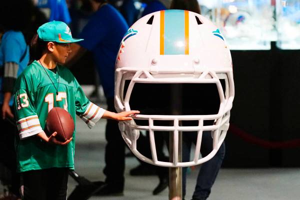 A Miami Dolphins fan touches an oversized Dolphins helmet at the Super Bowl Experience, the ope ...