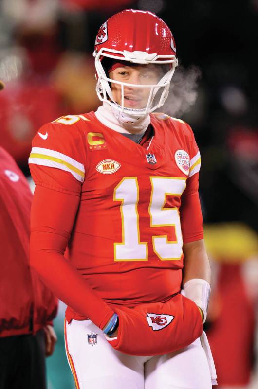 Kansas City Chiefs head coach Andy Reid, in back, watches his team during warmups in below-zero ...