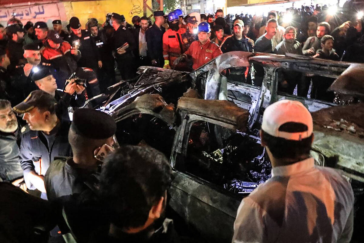 People, rescuers and security forces gather around a vehicle hit by a drone strike, reportedly ...