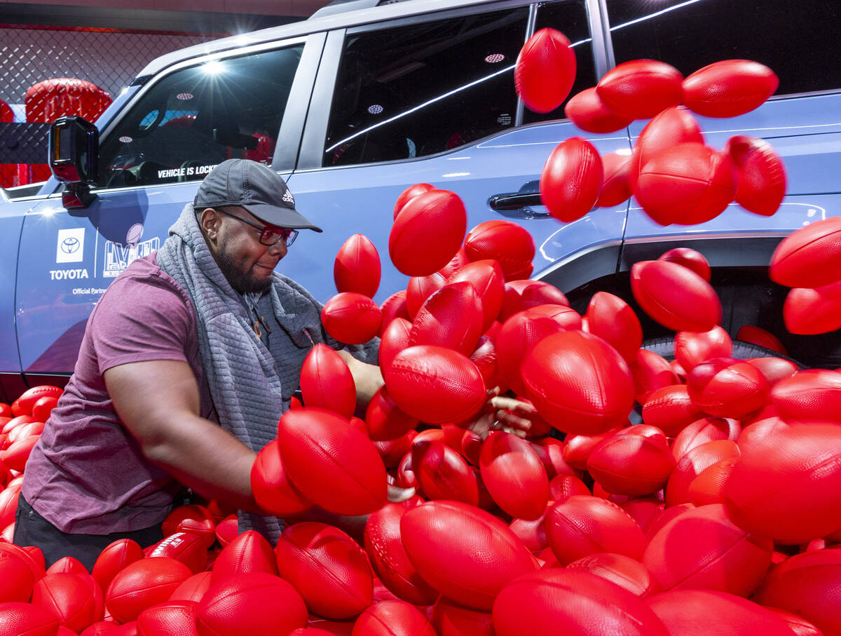 Julian Walker of Los Angeles digs through a pit of footballs looking for a hidden prize for the ...