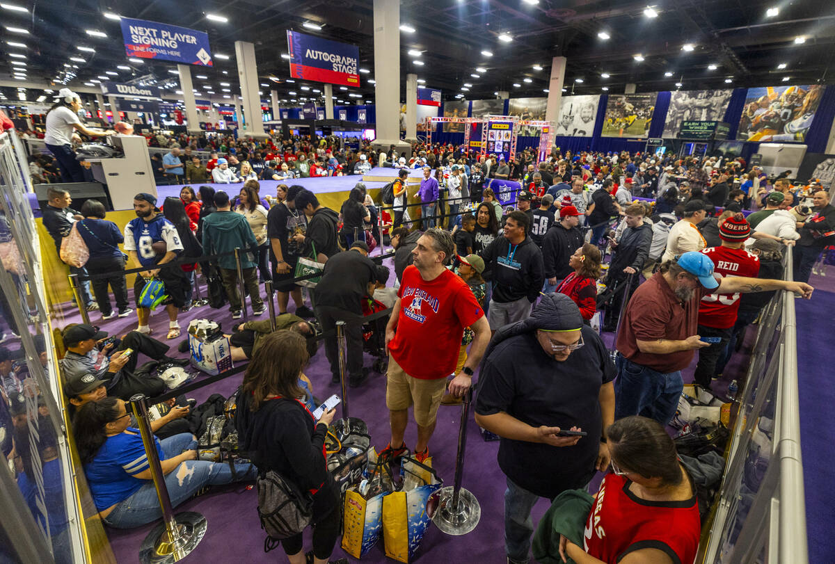 Fans pack together and patiently wait in line for the next football player due to arrive for au ...