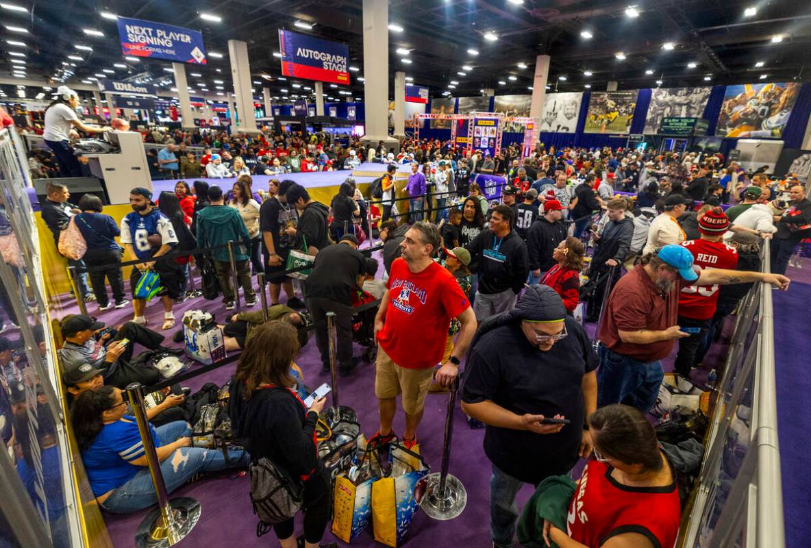 Fans pack together and patiently wait in line for the next football player due to arrive for au ...