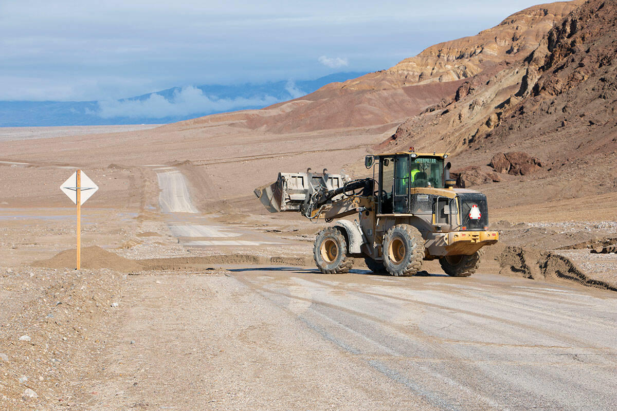 A National Park Service employee uses a loader to clear flood debris off Badwater Road at Death ...