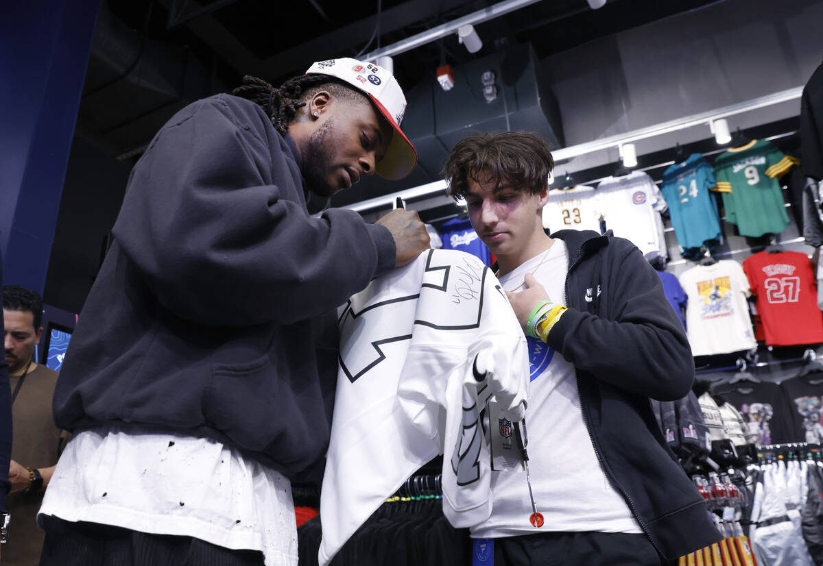 Raiders wide receiver Davante Adams signs an autograph to Judah Papa at the Lids Flagship Store ...