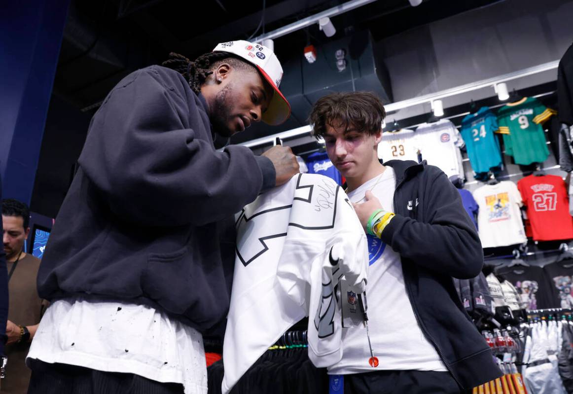 Raiders wide receiver Davante Adams signs an autograph to Judah Papa at the Lids Flagship Store ...