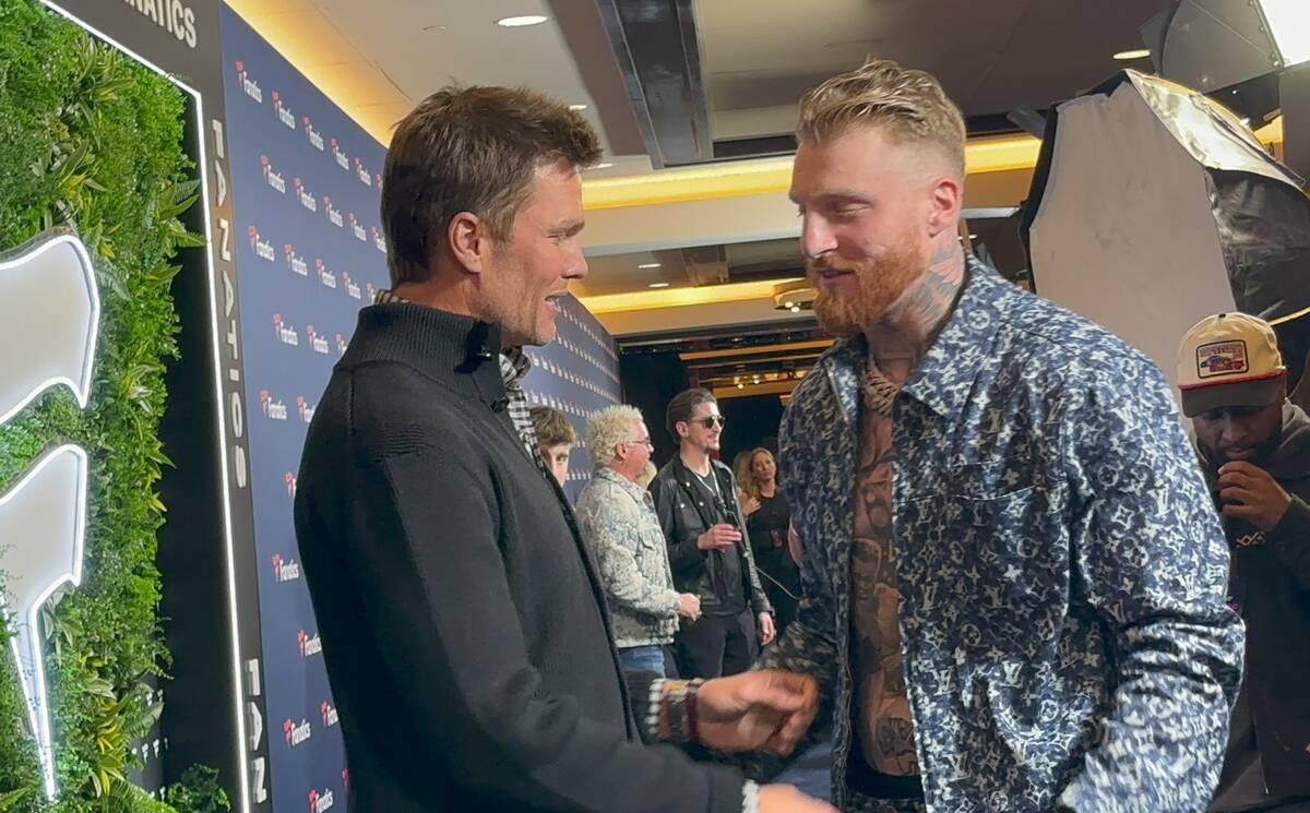 Former NFL star Tom Brady and Raiders defensive end Maxx Crosby greet each other on the blue ca ...