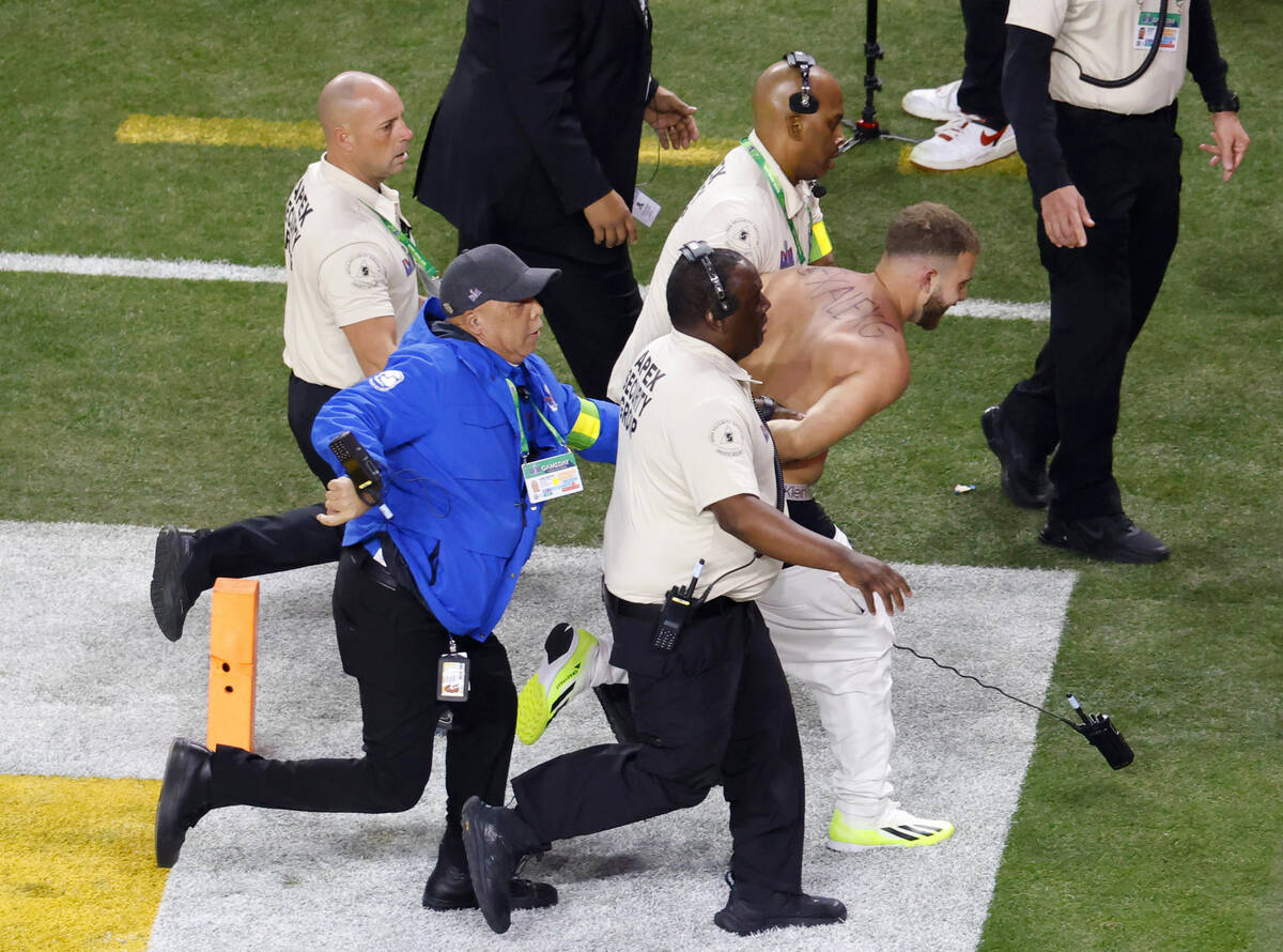 A shirtless man is escorted away by security after running on the field during Super Bowl 58, o ...