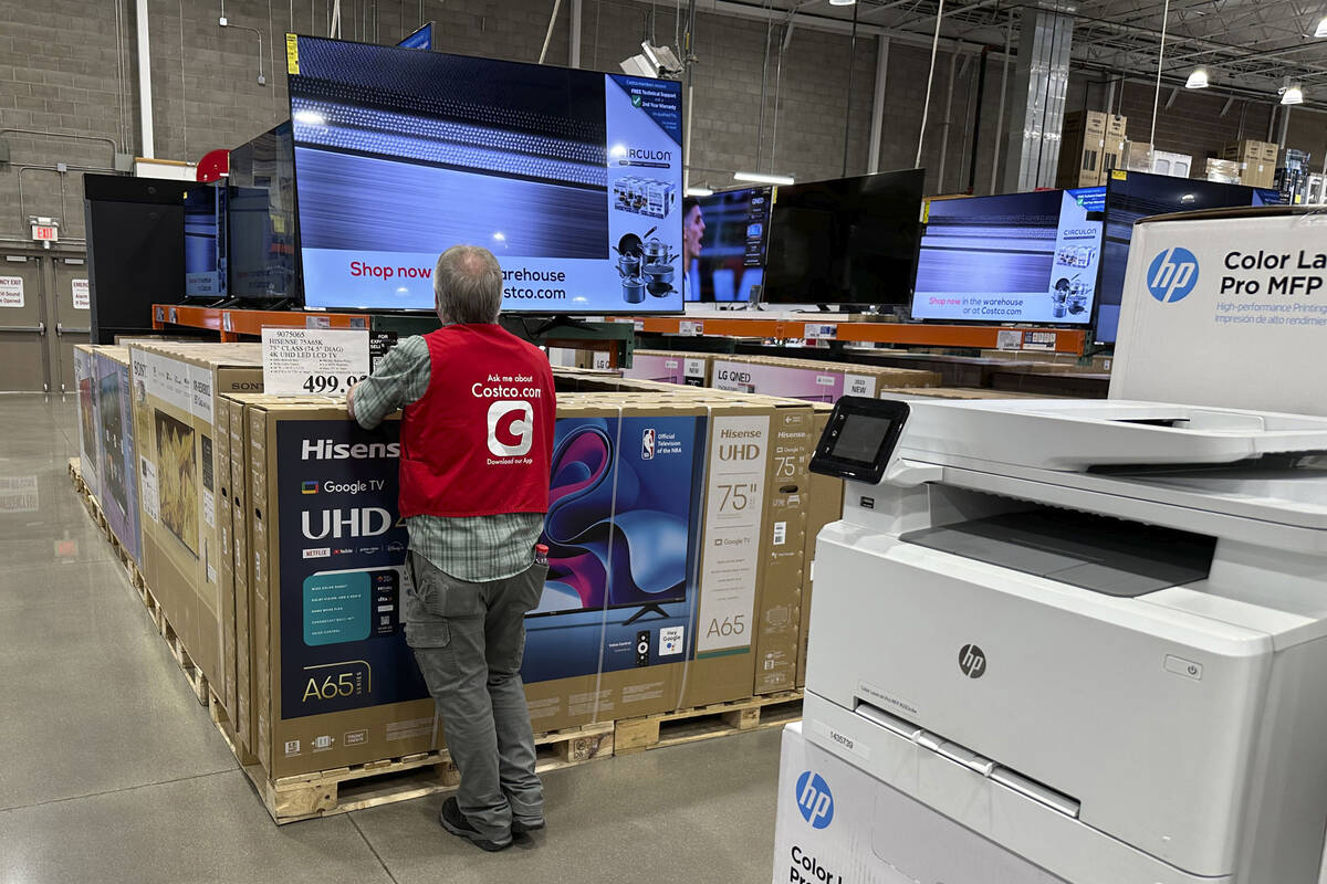 An associate checks over a big-screen television on display in a Costco warehouse Tuesday, Feb. ...