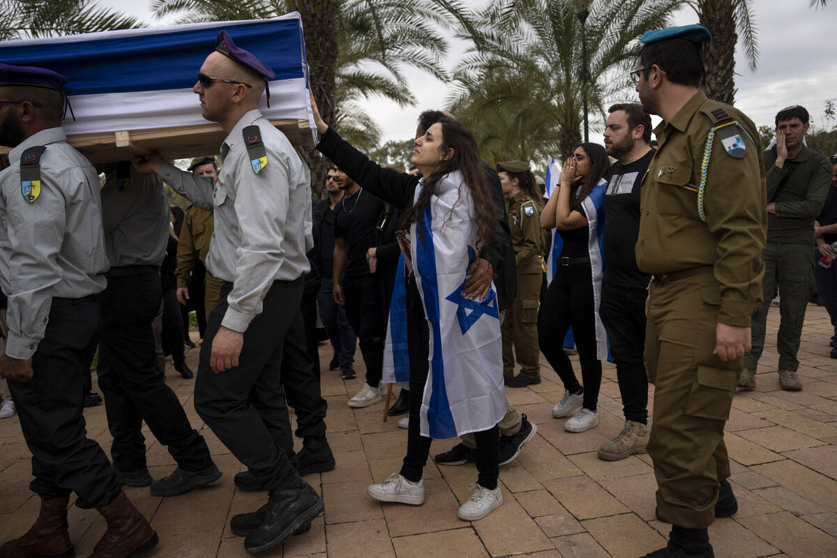 The wife of Israeli reservist Yair Cohen touches his flag-draped casket during his funeral at K ...