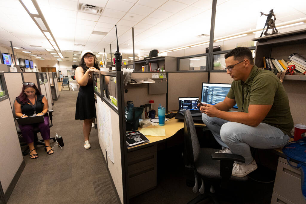 Reporters listen to a police scanner from the Las Vegas Review-Journal as police officers move ...