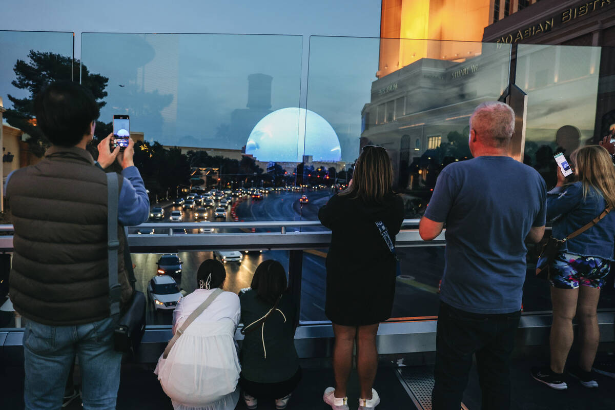 People stop on a pedestrian walkway to take photographs of the Sphere on Friday, Feb. 16, 2024, ...