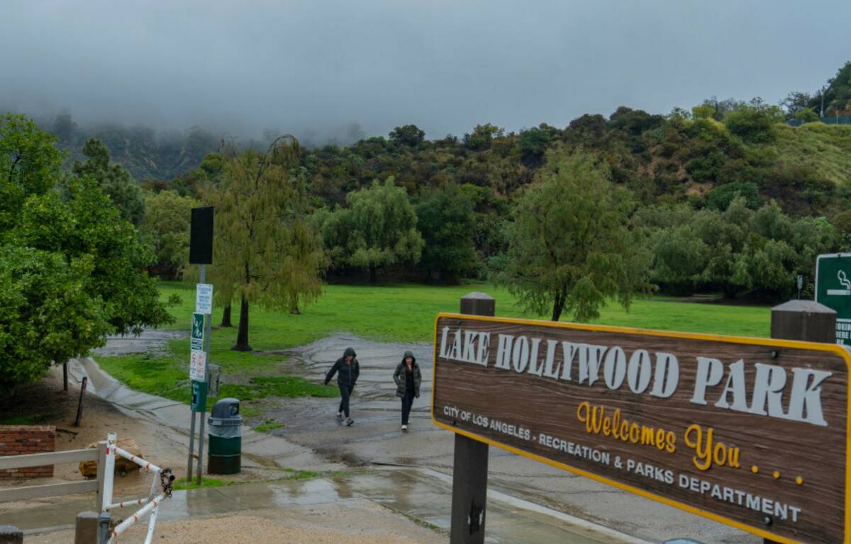 Tourists walk under the rain at Lake Hollywood Park covered by low clouds on Monday, Feb. 5, 20 ...