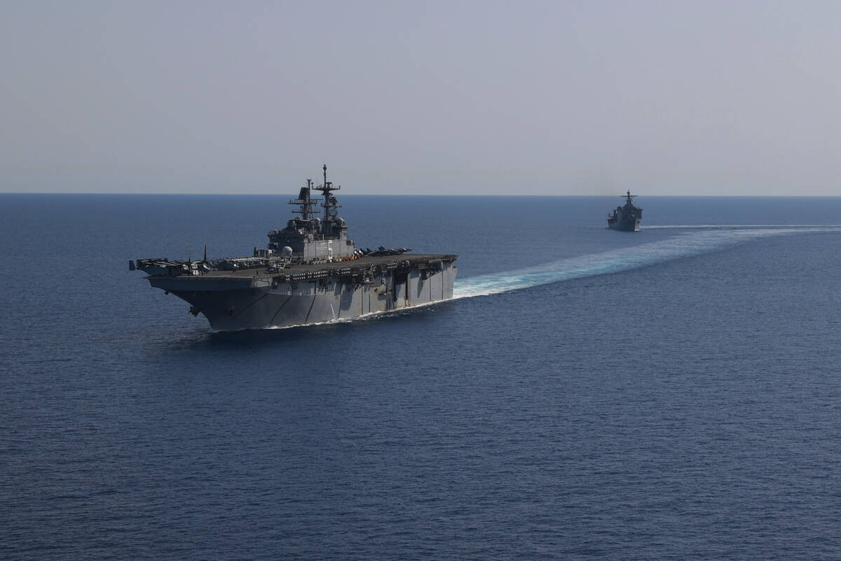 In this photo released by the U.S. Navy, the amphibious assault ship USS Bataan, front, and the ...