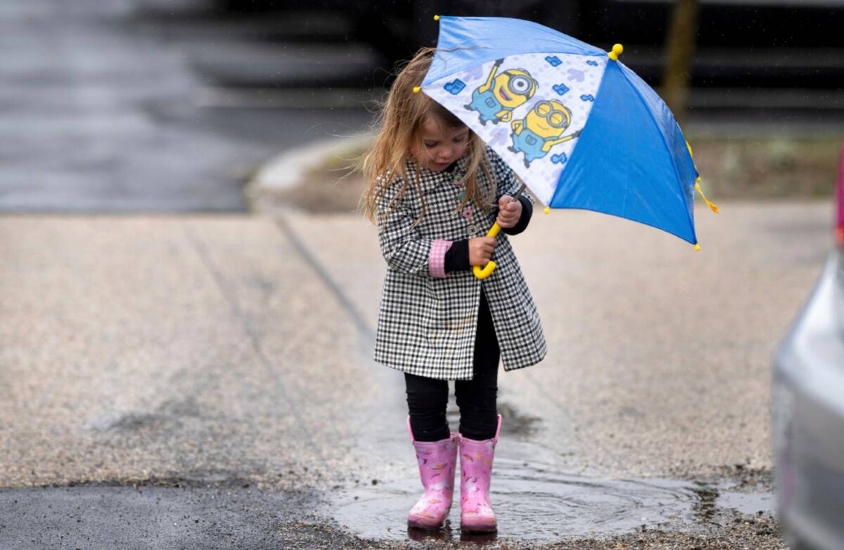 Kennedy Shoemaker, 2, of Simi Valley, tries out her rain gear on a puddle at the Ronald Reagan ...